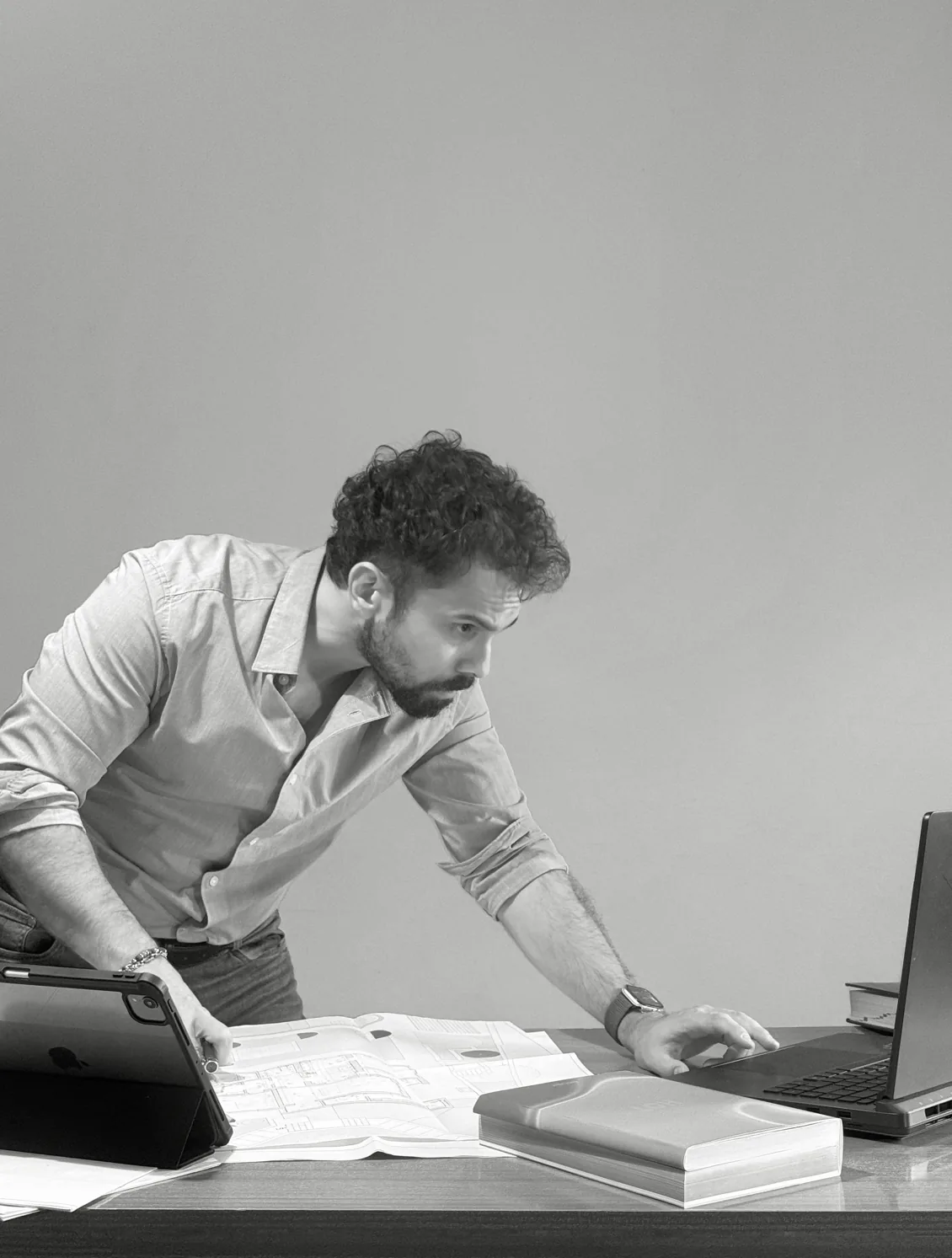 Roberto Dolfini al tavolo di lavoro, tra tavole di progetto e laptop