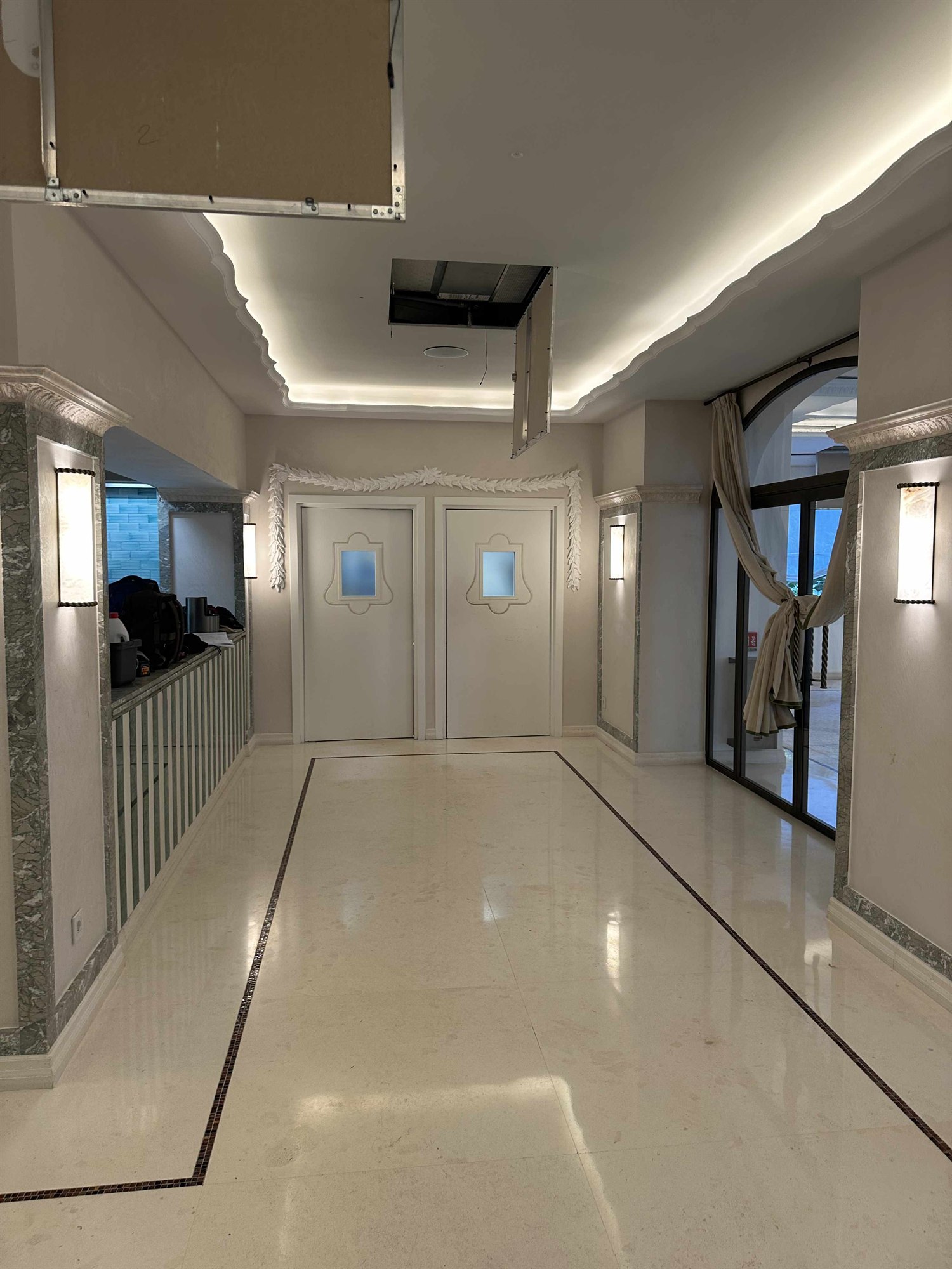 Foto dell'ingresso reale: doppia porta con festoni in stucco, lesene in marmo verde e vetrata ad arco