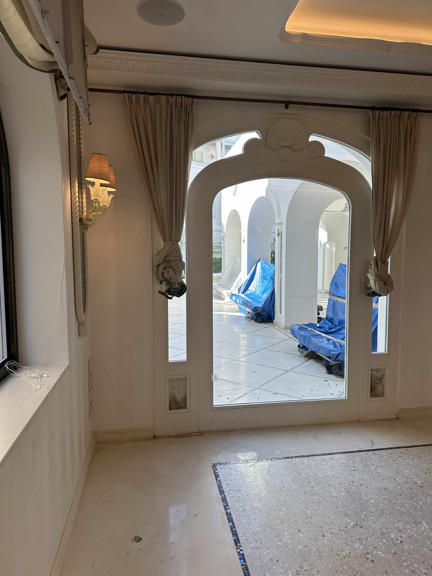 Foto del serramento reale ad arco con timpano a conchiglia, tende e affaccio sulla terrazza
